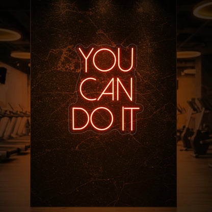 Photo of the 'YOU CAN DO IT' neon sign glowing in golden yellow against a styled interior wall.