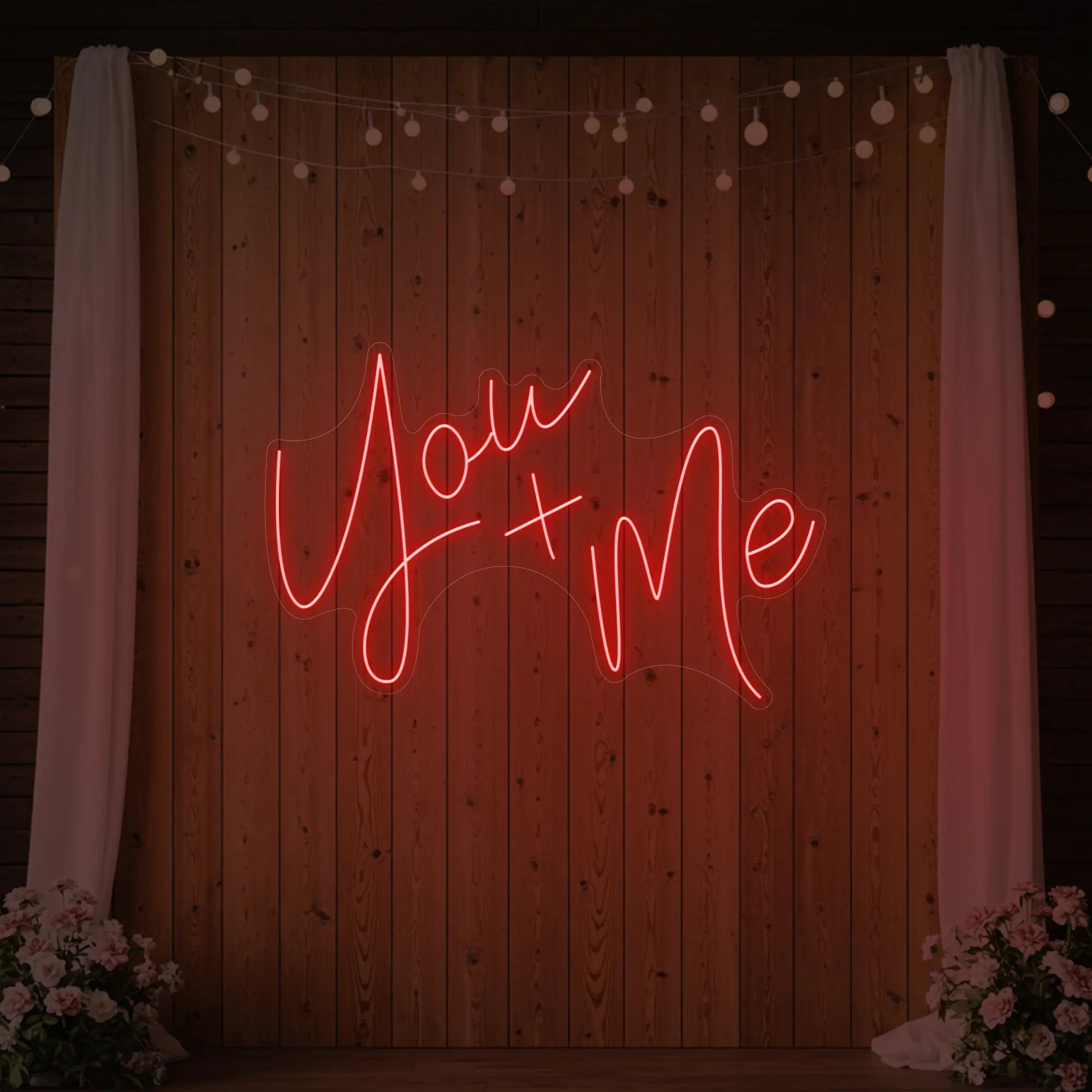  'You + Me' neon sign glowing in red against a styled interior wall.
