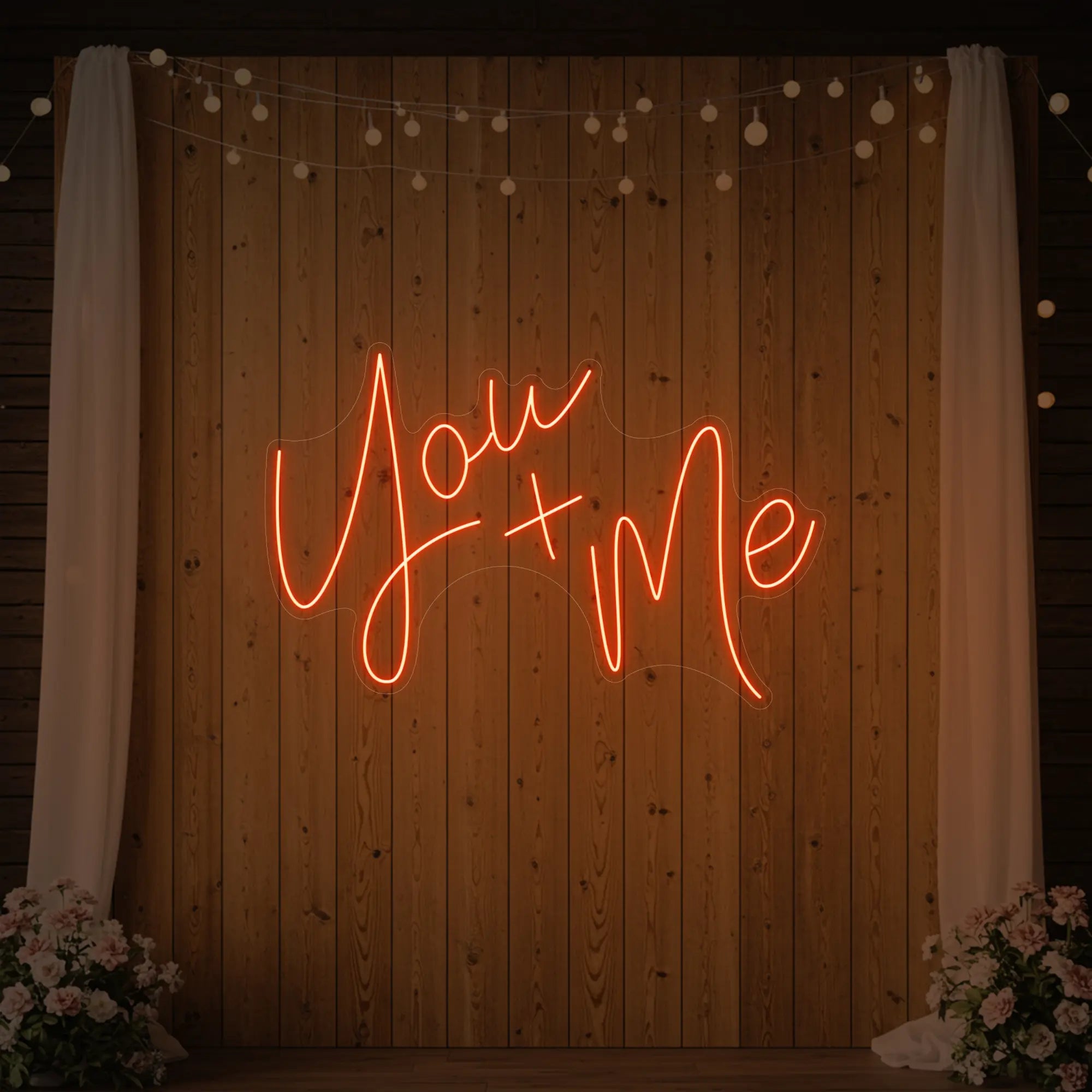  'You + Me' neon sign glowing in golden yellow against a styled interior wall.