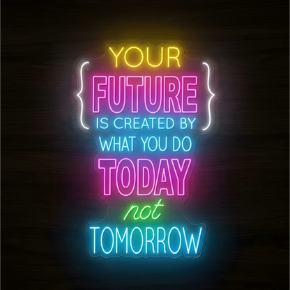 “YOUR FUTURE IS CREATED BY WHAT YOU DO TODAY not TOMORROW” LED Neon Sign with yellow, pink, cyan, green, and white lettering, white bracket-like accents, and clear acrylic backing against a dark wood background, suited to office and gym decor.